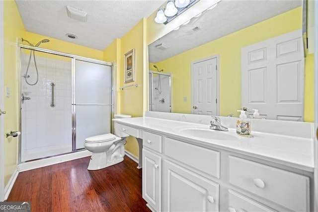 full bath with vanity, wood finished floors, a stall shower, a textured ceiling, and toilet