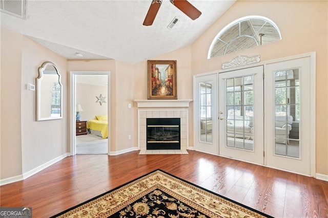 living area featuring visible vents, a ceiling fan, a textured ceiling, wood finished floors, and baseboards