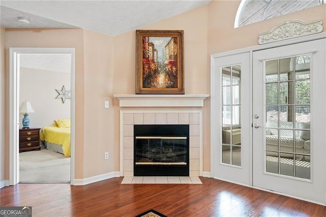 living room with baseboards, lofted ceiling, french doors, wood finished floors, and a textured ceiling