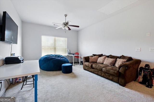 living area featuring a ceiling fan, attic access, and carpet