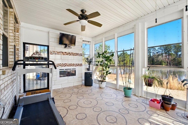 sunroom with a ceiling fan, wood ceiling, and a tile fireplace