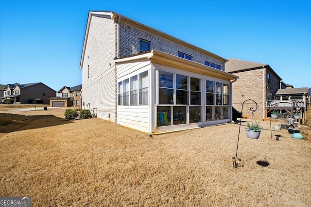 rear view of property with a yard and a sunroom