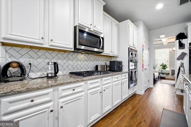 kitchen with visible vents, white cabinetry, appliances with stainless steel finishes, decorative backsplash, and dark wood-style flooring