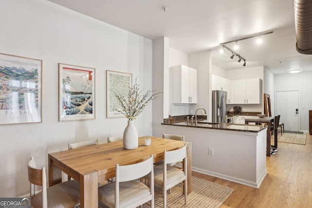 dining room with light wood-style flooring and rail lighting