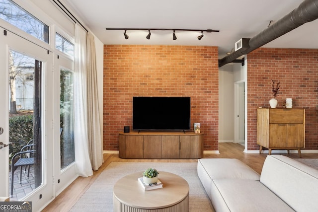 living room featuring wood finished floors and brick wall