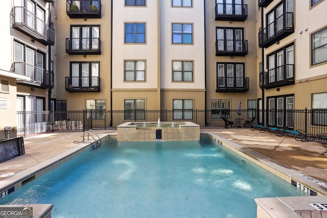 view of pool with a patio, a pool with connected hot tub, and fence