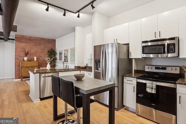 kitchen featuring white cabinetry, a peninsula, light wood-type flooring, and stainless steel appliances