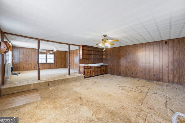 interior space with wooden walls, carpet flooring, and ceiling fan