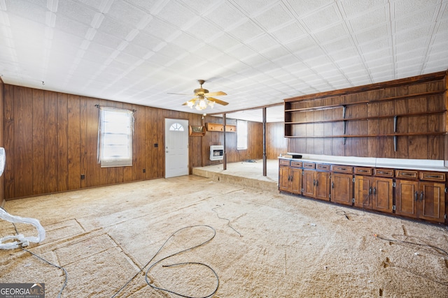 interior space featuring wooden walls, heating unit, and a ceiling fan