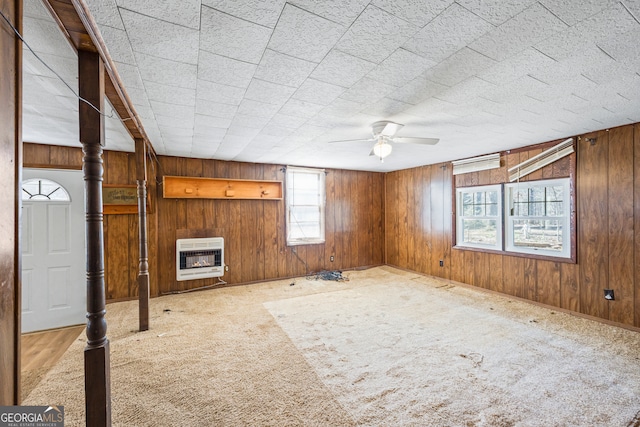 unfurnished living room with heating unit, a glass covered fireplace, and wood walls