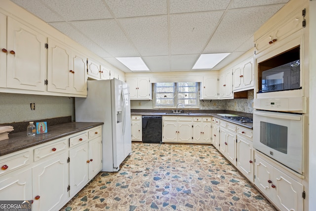 kitchen with a sink, a drop ceiling, dark countertops, and black appliances