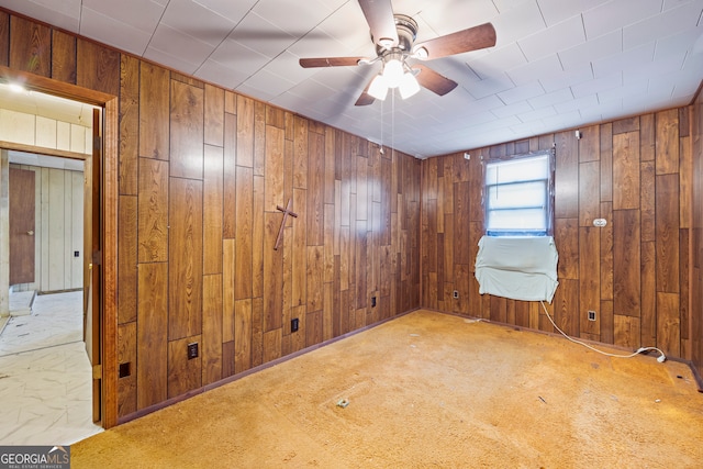 spare room featuring wooden walls, ceiling fan, and carpet flooring