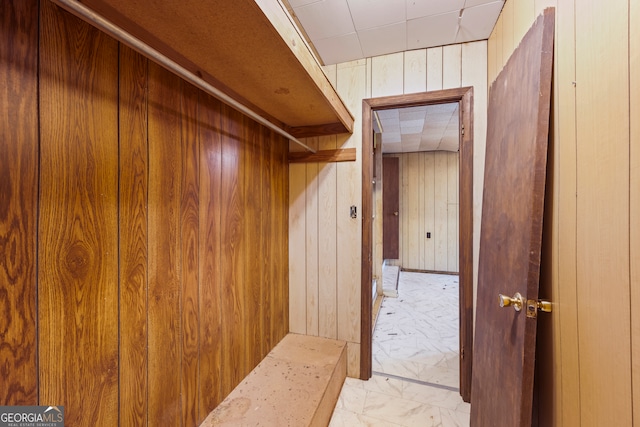 mudroom featuring wooden walls and marble finish floor