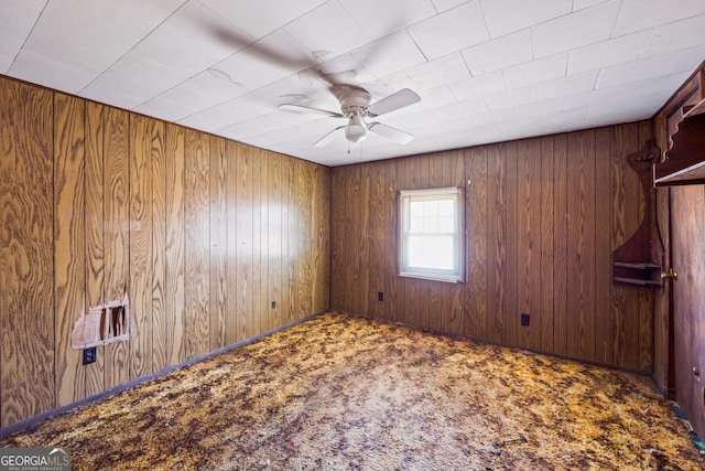 empty room with carpet floors, wooden walls, and ceiling fan