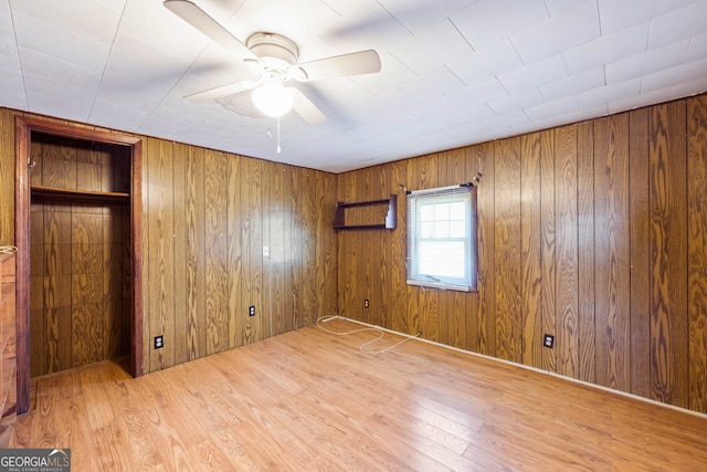 unfurnished bedroom featuring wooden walls, wood finished floors, and ceiling fan