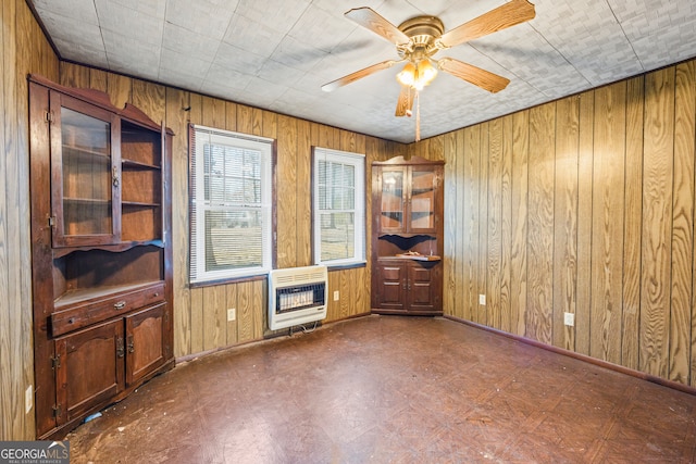 empty room featuring tile patterned floors, baseboards, wood walls, heating unit, and a ceiling fan