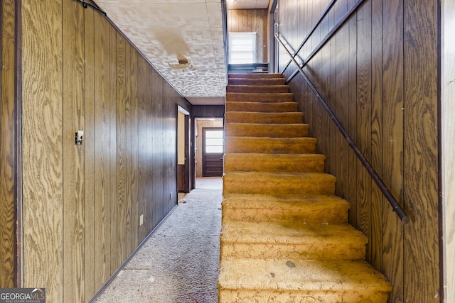 staircase with carpet and wood walls