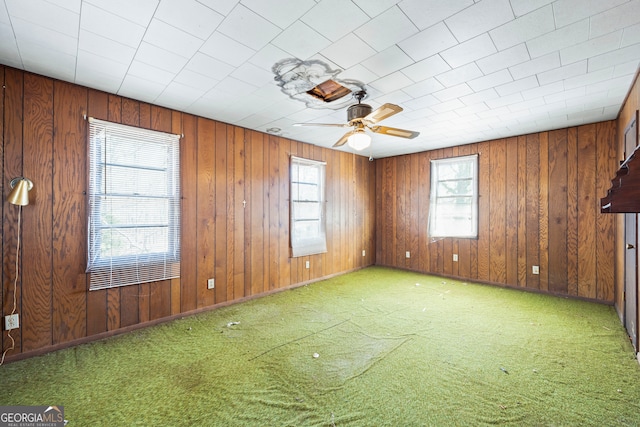 unfurnished room featuring wooden walls, carpet, and ceiling fan