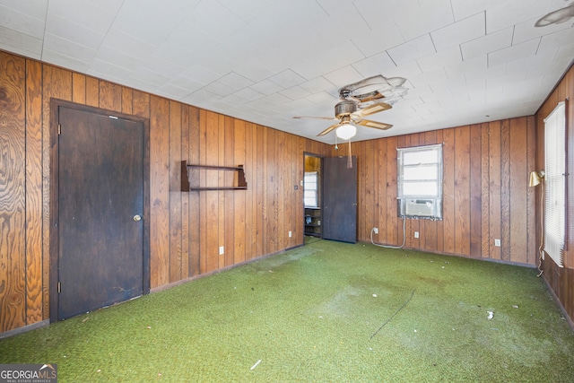 carpeted empty room with cooling unit, wooden walls, and ceiling fan