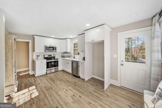 kitchen featuring a sink, stainless steel appliances, light wood-style flooring, and light countertops