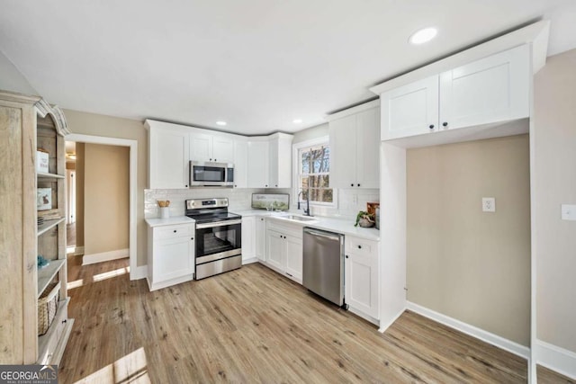 kitchen with a sink, stainless steel appliances, light wood-style flooring, and decorative backsplash