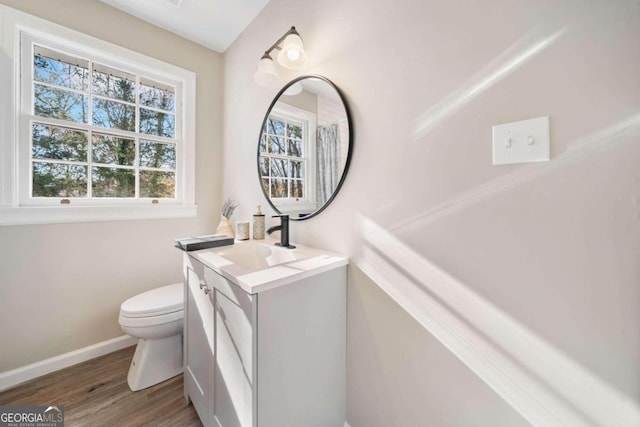 bathroom featuring toilet, vanity, baseboards, and wood finished floors