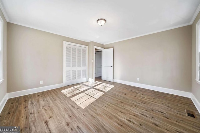 unfurnished bedroom featuring visible vents, baseboards, and wood finished floors