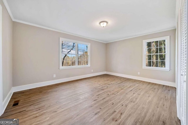 empty room with visible vents, plenty of natural light, baseboards, and wood finished floors