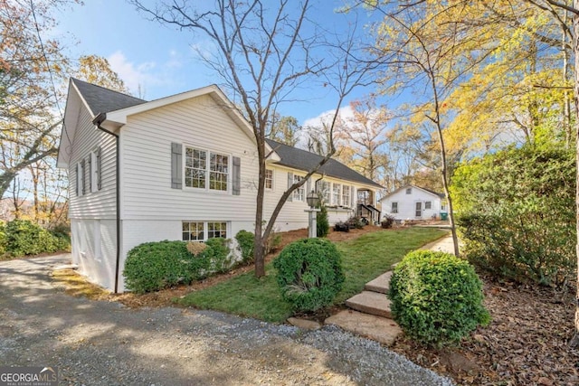 exterior space featuring aphalt driveway, a lawn, and brick siding