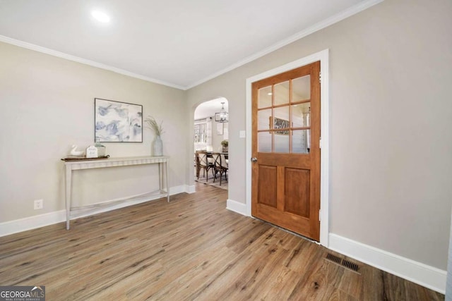 entryway with visible vents, ornamental molding, wood finished floors, arched walkways, and baseboards