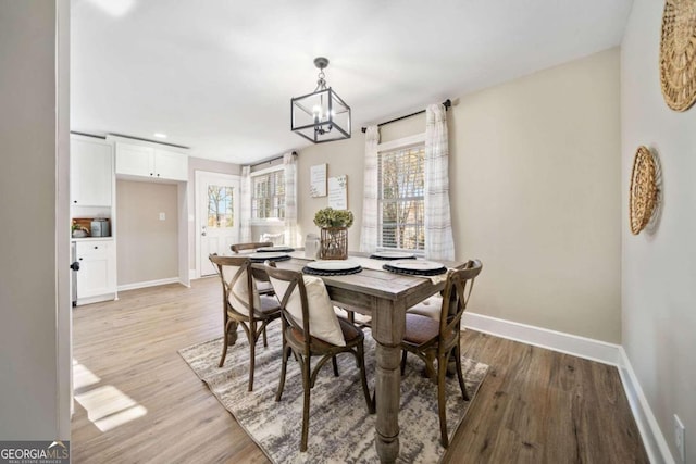 dining space with a chandelier, light wood-type flooring, and baseboards