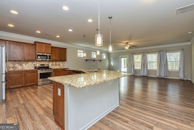 kitchen with visible vents, wood finished floors, brown cabinetry, stainless steel appliances, and a sink