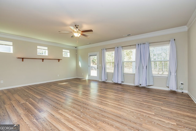 unfurnished room with a ceiling fan, wood finished floors, visible vents, baseboards, and crown molding