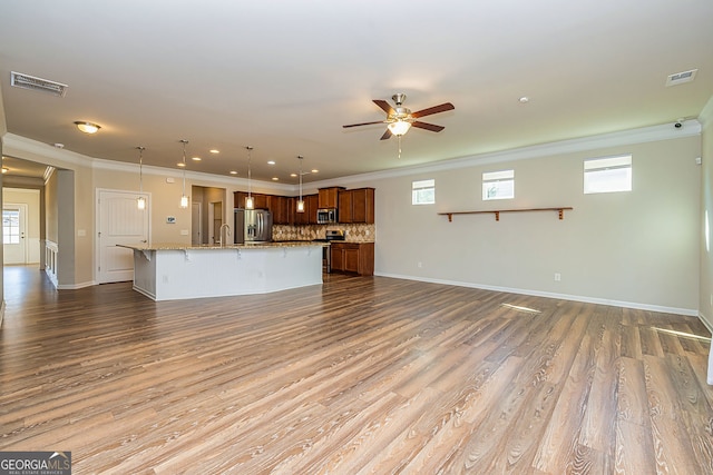 unfurnished living room featuring visible vents, a healthy amount of sunlight, wood finished floors, and a ceiling fan
