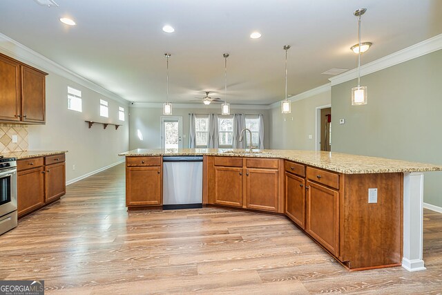 kitchen with light wood finished floors, brown cabinets, stainless steel appliances, a ceiling fan, and a sink