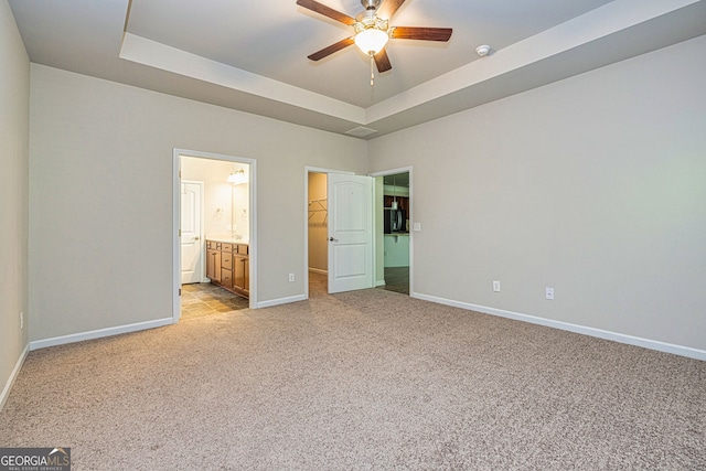 4 October Ave, Newnan, GA 30265 - unfurnished bedroom featuring light carpet, a tray ceiling, a spacious closet, a closet, and connected bathroom