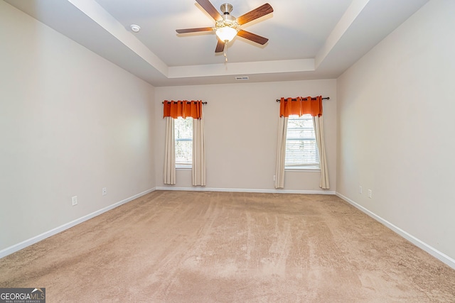 unfurnished room with plenty of natural light, baseboards, a tray ceiling, and a ceiling fan