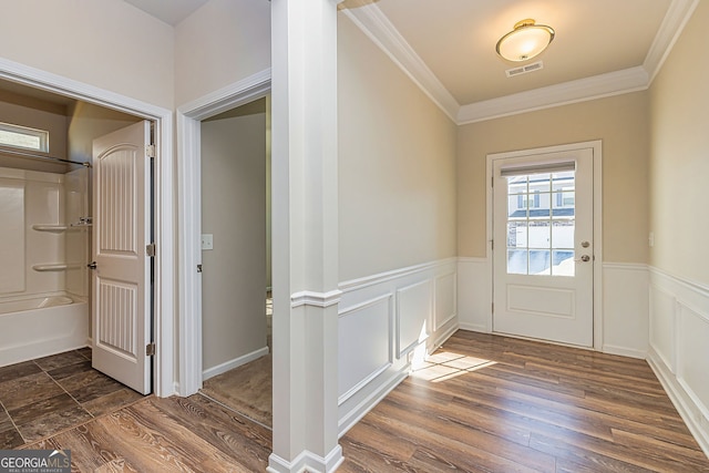 doorway featuring dark wood-style floors, visible vents, crown molding, and a wainscoted wall