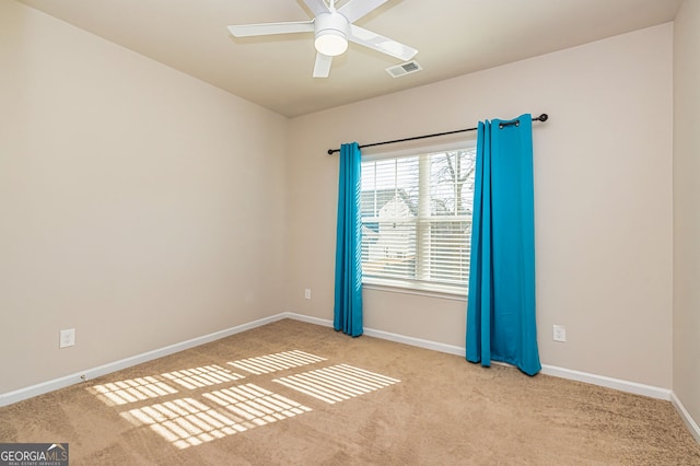 carpeted empty room featuring visible vents, a ceiling fan, and baseboards