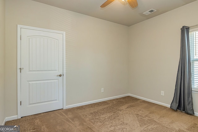 carpeted empty room featuring a ceiling fan, visible vents, and baseboards