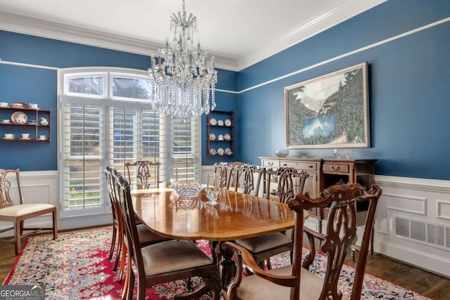 dining room with crown molding, wood finished floors, a wainscoted wall, and a chandelier