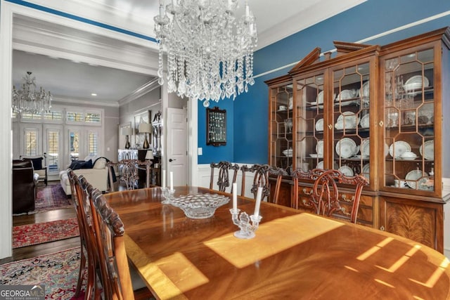 dining space featuring a chandelier, french doors, crown molding, and wood finished floors