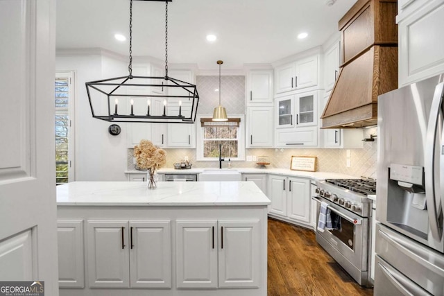 kitchen with a sink, backsplash, stainless steel appliances, white cabinets, and hanging light fixtures