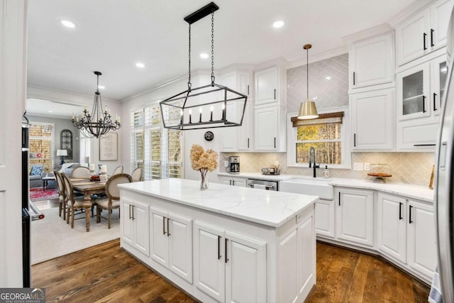 kitchen with a kitchen island, dark wood finished floors, a sink, white cabinets, and crown molding