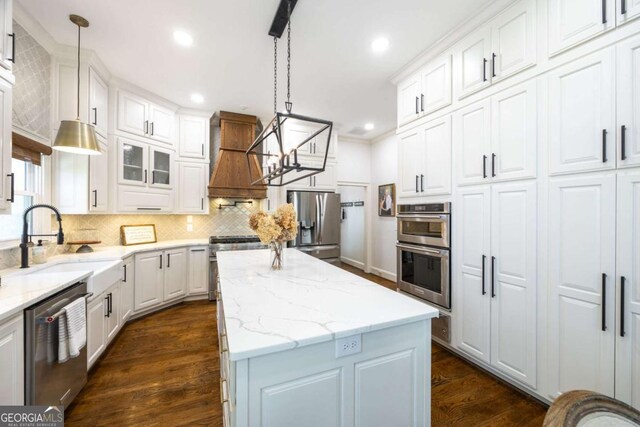 kitchen with stainless steel appliances, a kitchen island, and white cabinets