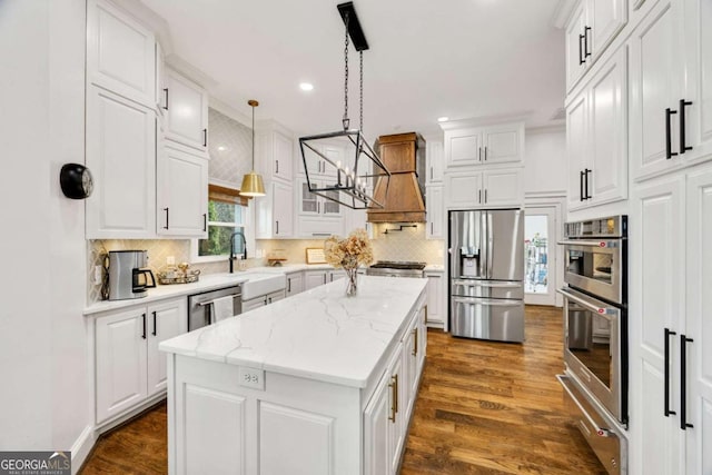 kitchen featuring a sink, a kitchen island, dark wood-style floors, appliances with stainless steel finishes, and white cabinets