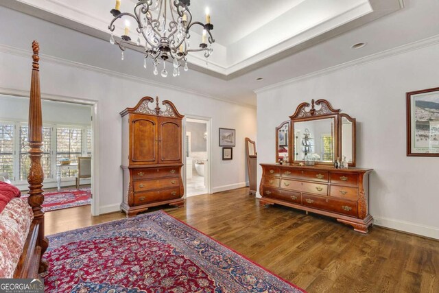 bedroom with a tray ceiling, crown molding, and wood finished floors