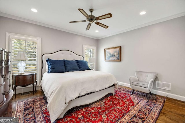 bedroom featuring wood finished floors, visible vents, baseboards, and ornamental molding