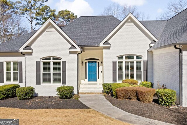 view of front of property with brick siding and roof with shingles