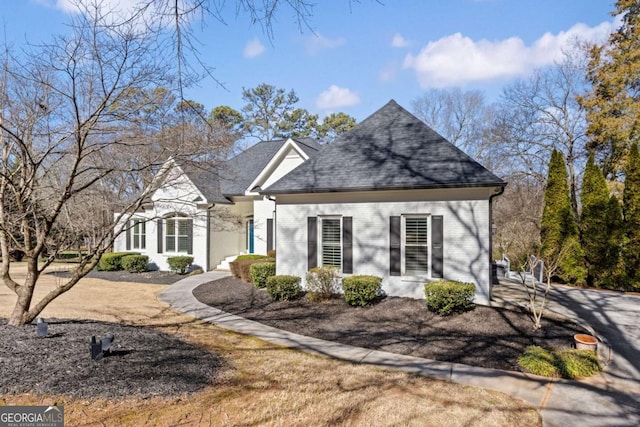 view of front of home with brick siding and roof with shingles